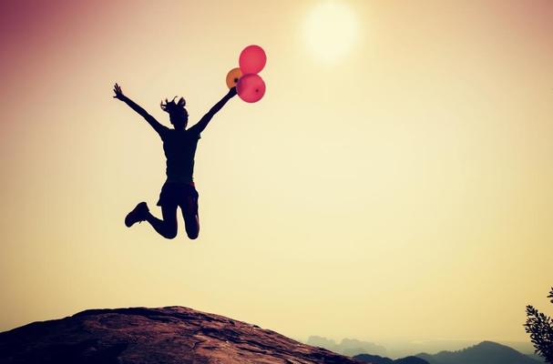 Woman jumping with balloons in celebration