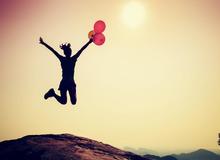 Woman jumping with balloons in celebration